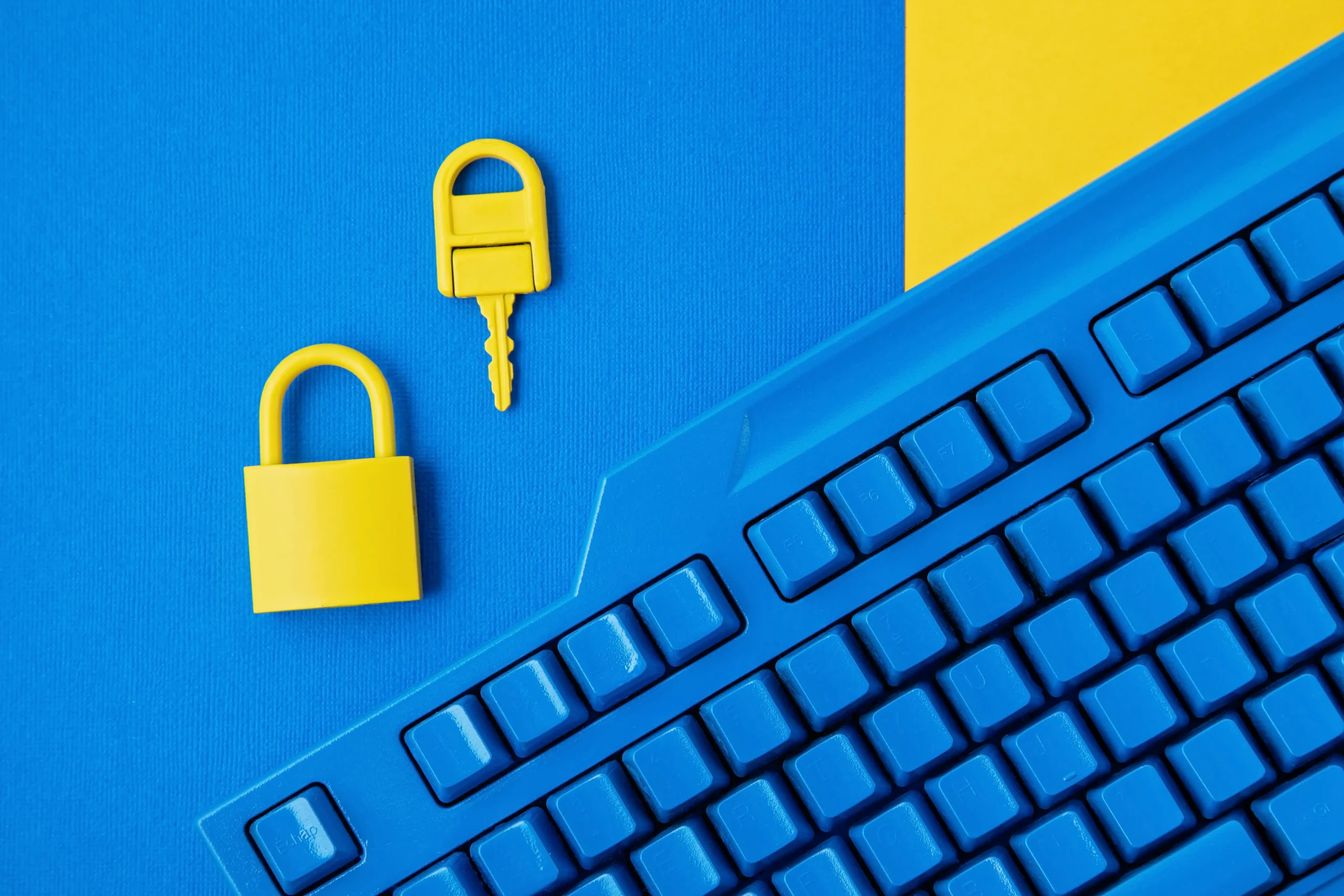 Zila tastatūra ar dzeltenu piekļuves atslēgu un piekaramo slēdzeni – simbolizē IT drošību un piekļuves kontroli